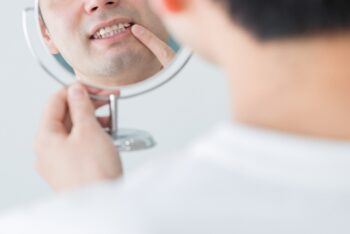 鏡で自分の歯を確認している男性